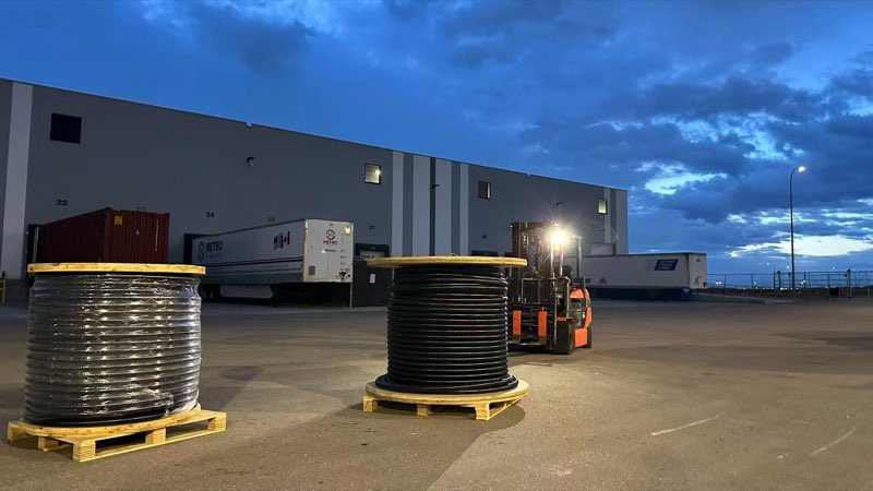 Reels of power cable on pallets in the yard of SMK’s Calgary warehouse, with a forklift