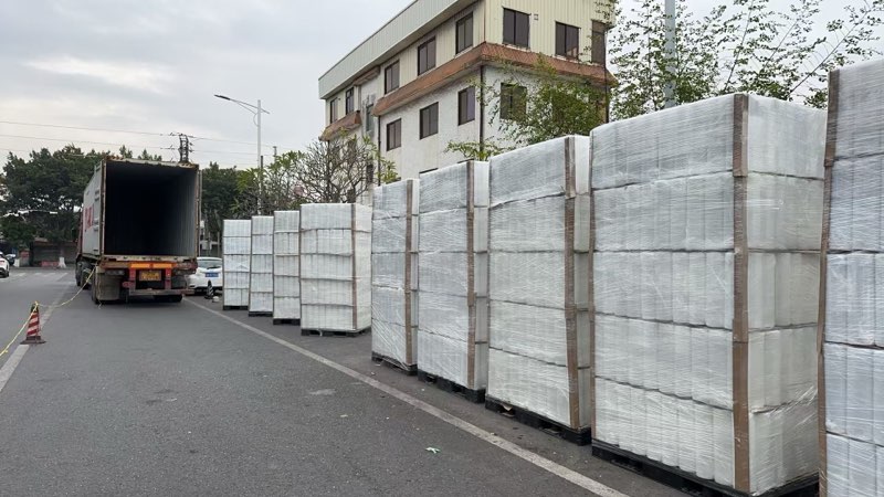 Shrink-wrapped pallets of plastic packaging film lined up for loading at the supplier