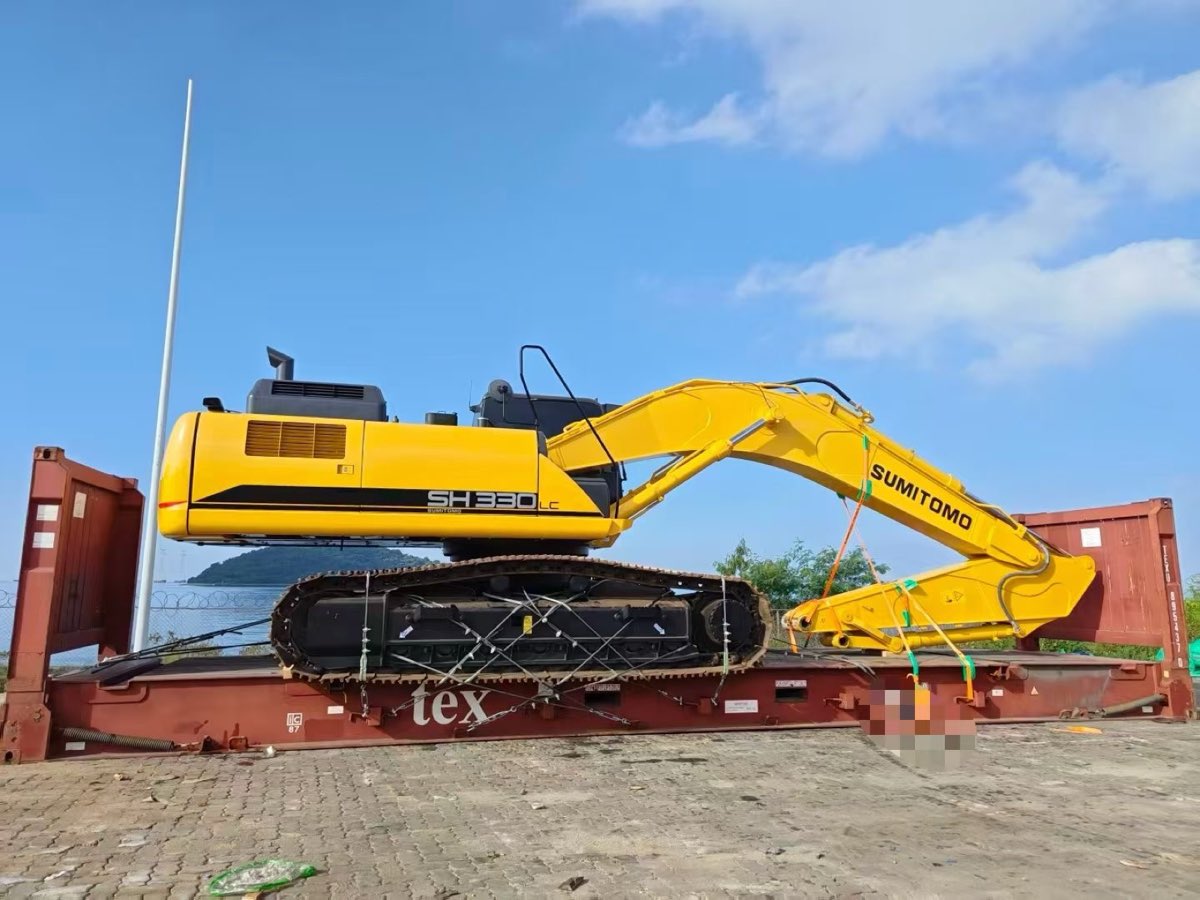 Sumitomo SH330LC excavator on a flat-rack with its boom lowered and lashed